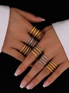 Detail of stacked two-tone gold and silver minimalist stainless steel rings on hand