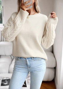 Dettaglio ravvicinato delle maniche a treccia di un maglione girocollo panna da donna