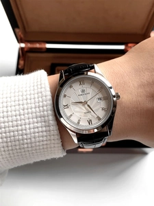 Close-up of quartz men's watch with silver case, black leather strap, and date display