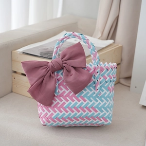 Detail view of woven gift basket with colorful patterns and a large pink fabric bow