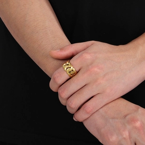 Close-up of 18k gold plated Cuban chain ring on male finger with rugged metal texture
