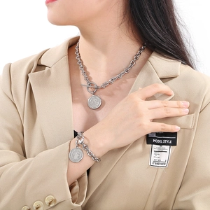 Detail of silver chunky chain necklace and bracelet set with round coin pendant on a model