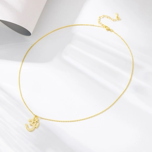 Close-up of golden S925 silver Om symbol pendant necklace with fine chain detail