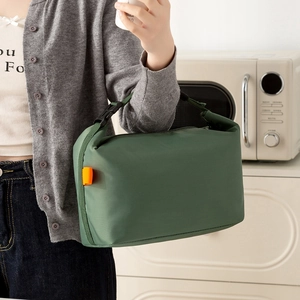 Insulated dark green lunch bag with black handle and buckle shown in kitchen setting