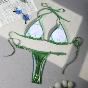 Detailed flat lay of metallic green bikini with pearl-sheen fabric and gold ring accents