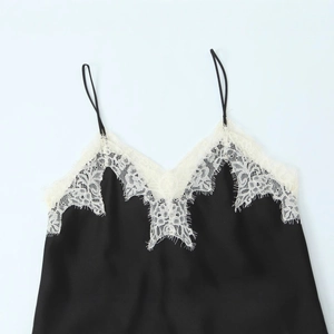 Elegant black satin camisole with white lace trim and thin straps in a minimalist style