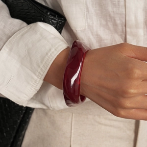Gros plan d'un bracelet en acrylique bordeaux translucide épais au design organique