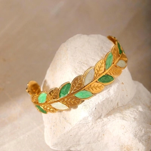 Detailed view of leaf shaped enamel inlay on a gold plated stainless steel open bangle