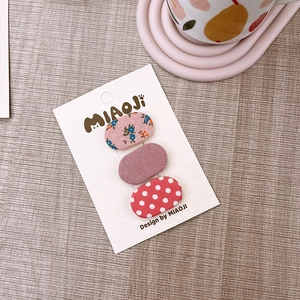 Dettaglio di fermagli per capelli in tessuto a fiori e pois su confezione regalo di marca