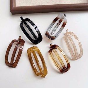Flat lay of six glossy acrylic oval hair clips in assorted colors on white background