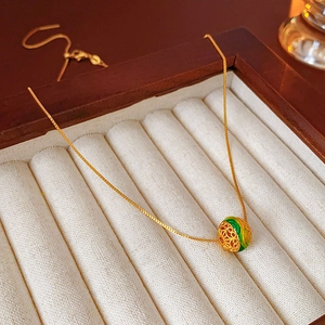 Primo piano del ciondolo a perla cava placcato oro 18K con inserto verde su velluto