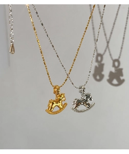 Detail of rocking horse pendants in gold and silver finishes on minimalist chains