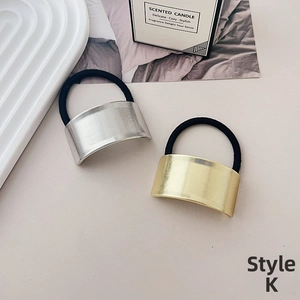 Close-up of gold and silver metallic elastic hair ties with brushed texture on white tray
