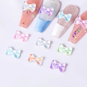 Detail view of aurora macaron bow nail charms applied on soft-colored nail tips