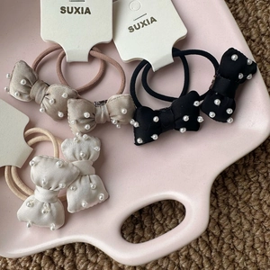 Three-pack bow hair ties with hand-sewn pearls in champagne, black, and off-white colors