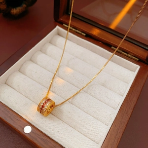 Detail of gold-plated waist pendant necklace with red crystals on a velvet jewelry box