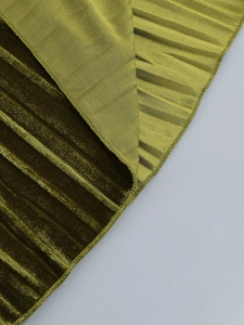 Gros plan sur un tissu plissé vert métallisé avec reflets soyeux et plis accordéon