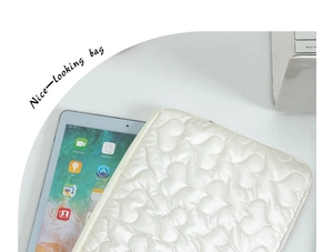 Close-up of white quilted laptop sleeve with heart stitching and secure zipper closure