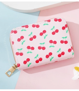 Detailed top view of a pink coin purse with red cherry print and golden zipper teeth