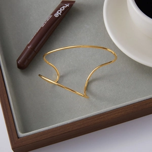 Minimalist gold-plated stainless steel open bangle featuring sleek geometric streamlines