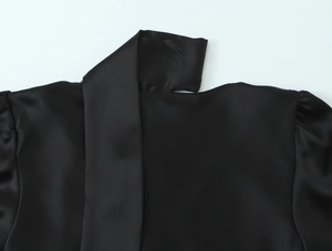 Close-up of the elegant neckline on a black satin shirt with smooth silky texture