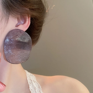 Macro view of oversized translucent dark purple textured resin earrings on model