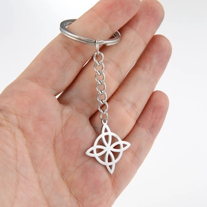 Poliertes Edelstahl-Schlüsselanhänger mit Hexenknoten, in der Hand auf weißem Grund