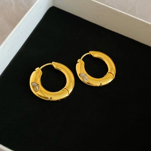 Detail of gold-plated hoop earrings with irregular texture and marquise-cut zircon stones