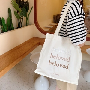 Détail de la broderie beloved sur un sac fourre-tout en toile crème avec bandoulière