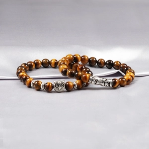 Tiger eye bead bracelet with antique silver owl charms on soft grey satin background