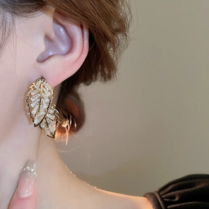 Gros plan de boucles d'oreilles feuilles d'or avec pavé de zircons sur un mannequin