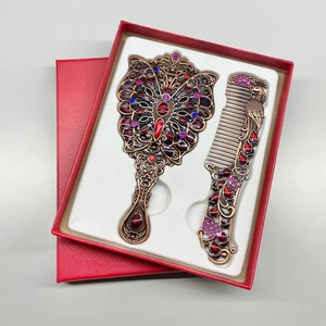 Detail of vintage peacock makeup mirror and comb set in a red textured gift box