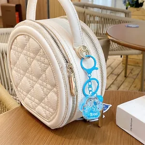 Blue cat paw quicksand keychain with glitter on a white leather handbag in cafe setting