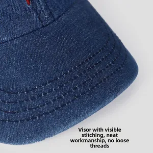 Detail of multi-row stitching on the brim of a dark blue denim baseball cap