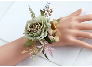 Detailed view of a Morandi green artificial rose wrist corsage with ribbons for weddings