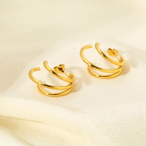 Détail des boucles d'oreilles clous triple couche en acier doré en forme de C sur soie