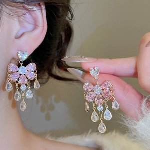 Detail of elegant gold earrings with pink crystals and cascading water drop tassels