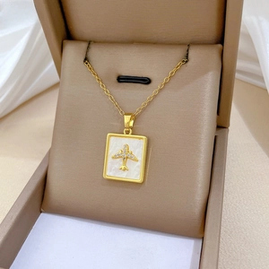 Macro detail of gold rectangle necklace with shell inlay, crystal pavé and airplane motif