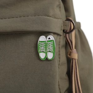 Detail of green canvas sneaker enamel pin with heart on an olive textured bag