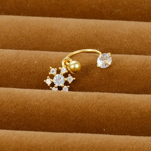 Macro detail of golden snowflake belly ring with zircons on brown velvet jewelry box