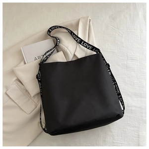 Close-up of black nylon crossbody bag with LOVE printed strap on beige aesthetic background