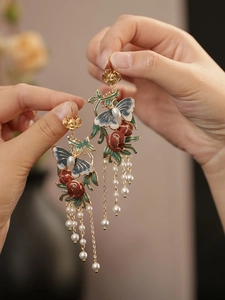 Détail de boucles d'oreilles papillon en émail vintage avec longs glands en perles