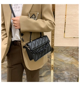 Sac bandoulière noir matelassé avec chaîne épaisse porté par un mannequin chic