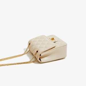 Detail view of beige quilted PU leather crossbody bag with gold chain and twist lock