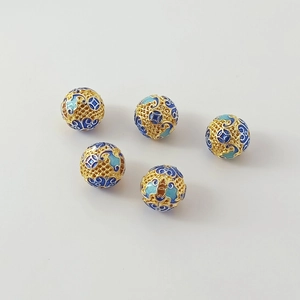 Macro view of five 18K gold hollow cloisonne enamel beads with intricate floral patterns