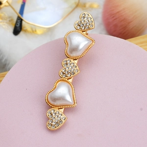Gros plan détaillé d'une barrette dorée en forme de cœur avec perles et strass