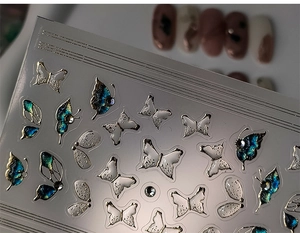 Macro shot of 5D embossed butterfly nail stickers with metallic silver and blue-green hues