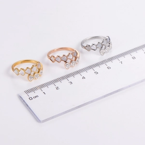 Three minimalist heart-shaped rings in gold, silver, and rose gold with zircon inlay