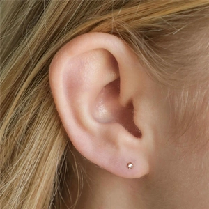 Close-up of a gold S925 silver stud earring with a round crystal on a model's ear