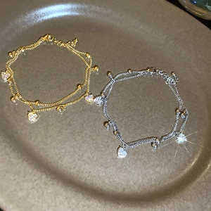 Detail of 18k gold plated double-layer chain bracelet with sparkling zircon heart pendant